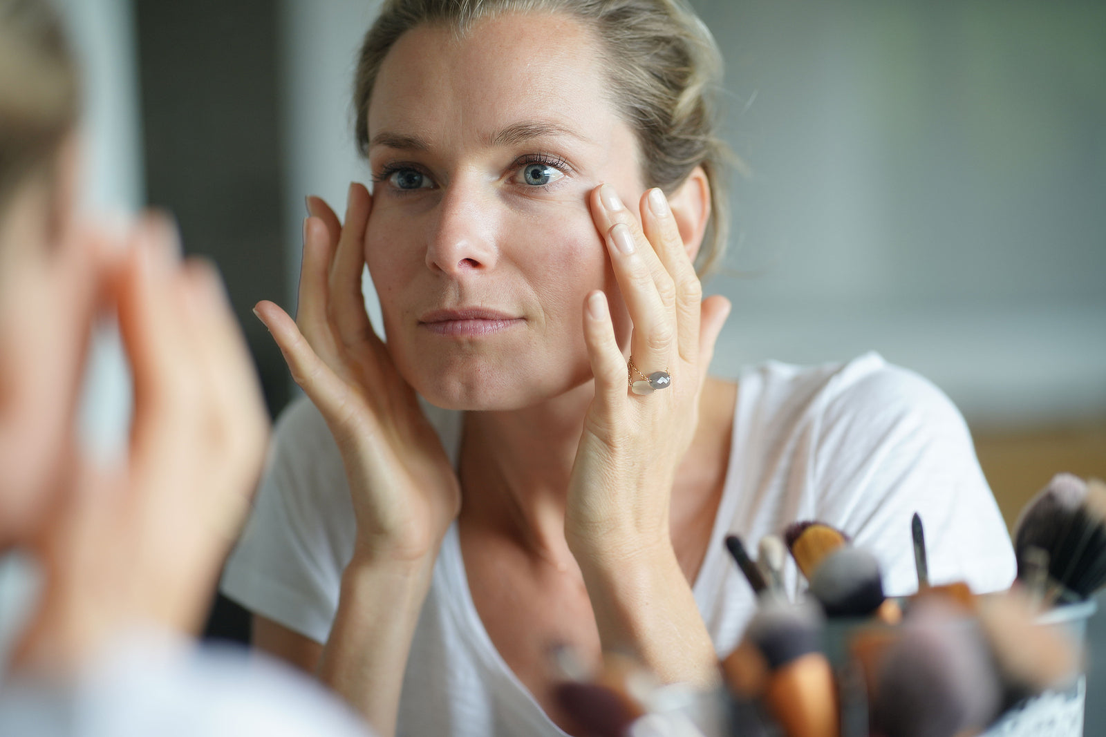 Woman looking at face in the mirror - common skin care concerns