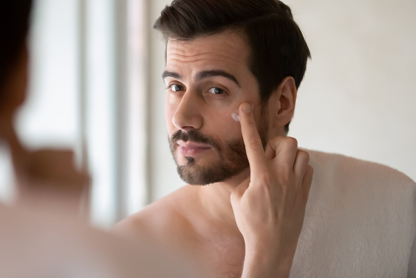 Man putting skincare product on his face
